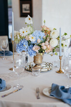 Blue Wedding Decor. Festive Table Decorated With Flowers On The Center, Candles, Silverware And Plates With Silk Napkins On Dusty Blue Tablecloth