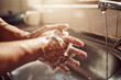 © Clement Coetzee/peopleimages.com - No germs, no problem. Shot of an unrecognisable man washing his hands in the kitchen sink at home.