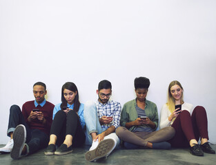 Wall Mural - Theyve got a few minutes before class. Full length shot of a group of university students sitting in a corridor on campus.