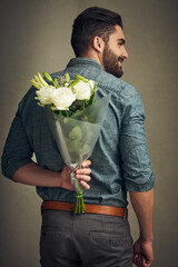 Poster - She deserves to feel special. Studio shot of a handsome young man holding a bunch of flowers behind his back.