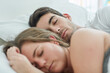 © Nola V/peopleimages.com - No need to rush today. Shot of a relaxed young couple sleeping in bed together at home.