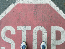 Two Feet On Stop Sign On Asphalt
