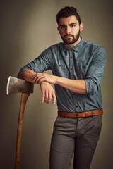 Poster - Tantalizingly tough. Studio shot of a young man posing with an axe against a green background.
