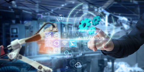 Wall Mural - Automation smart robotic industry 4.0 concept.Man hands pointing at virtual blue gears on blurred robot arm and factory as background