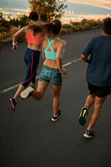 Fototapete - Meet up and get your sweat on. Shot of a fitness group running along a rural highway.