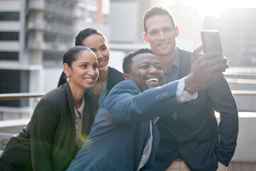 Canvas Print - Getting the team spirit going. Shot of a group of businesspeople taking a selfie against a city background.