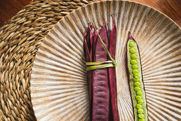 Wall Mural - Bundle of purple Guaje bean pods on a plate next to an open bean pod with exposed seeds. Oaxaca, Mexico.