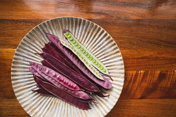 Wall Mural - Pile of purple Guaje pod seeds on a plate in Oaxaca Mexico. There is an open pod with seeds inside.