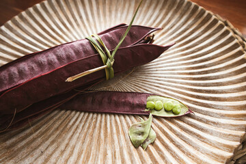 Wall Mural - Bundle of purple Guaje bean pods on a plate next to an open bean pod with exposed seeds. Oaxaca, Mexico.