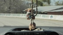 A Toy Giraffe and Rosary Hanging from the Rear View Mirror of a Car on Road in Jujuy Province, Argentina. Close Up.  