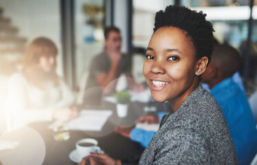Poster - Theyre a company of the best creatives. Portrait of a young businesswoman sitting in an office with colleagues in the background.