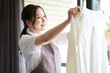 窓際で洗濯物を干すアジア人女性