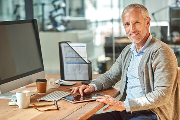 Poster - Getting down to work with a smile. Portrait of a smiling mature businessman sitting at his desk in an office.