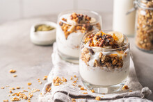 Crunchy Granola With Yogurt, Banana, Nuts, Chocolate And Honey In A Glass On White Background. Healthy Breakfast Concept.