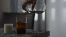Pour Cold Brewed Coffee In Tumbler Glass With Ice Ball On Wood Table