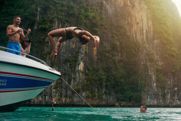 Aufkleber - No risk, no reward. Shot of a young woman doing a backflip off a boat while her friends watch.