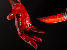 Man Holding Knife With Bloody Hand On Black Background. 