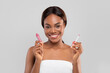 © Prostock-studio - Happy pretty young african american female with perfect skin in towel hold lip gloss and brush