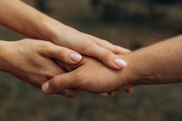 Handshake of husband and wife. The girl holds the guy's hand with both hands. Love in an embrace