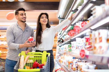 Wall Mural - Happy Arabic Spouses Buying Food During Grocery Shopping In Supermarket