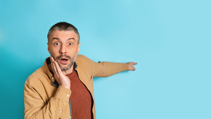 Poster - Shocked Man Pointing Finger Aside At Empty Space, Blue Background