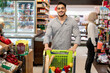 Cheerful Egyptian Man Doing Grocery Shopping Walking In Modern Supermarket