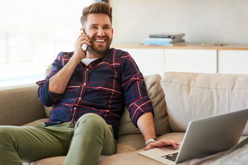 Poster - Staying productive even on his days off. Shot of a young man using a laptop and mobile phone on the sofa at home.