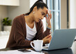 © Nina Lawrenson/peopleimages.com - Working from home sure is a pain some days. Shot of a young woman looking stressed while working on her laptop at home.