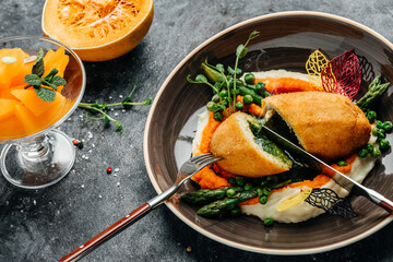 Chicken Kiev cutlet breast stuffed with butter, garlic and herbs served with asparagus and peas. Food recipe background. Close up