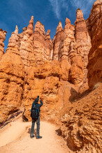 United States, Utah, Bryce Canyon National Park, Rear View Of Senior Hiker With Backpack Photographing Hoodoos In Bryce Canyon National Park