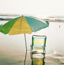 Beach Chair And Umbrella On Beach At Sunset