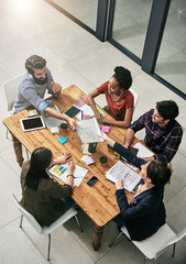 Passing around important paperwork. High angle shot of a group of colleagues having a meeting in a modern office.