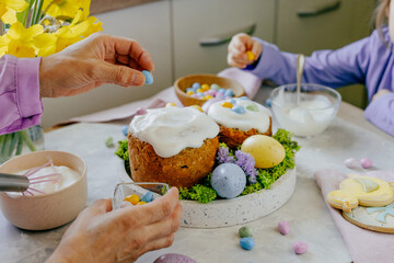 Grandmother and granddaughter decorating Easter cakes with chocolate eggs