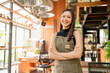 © whyframeshot - portrait of asian adult female woman wear apron standing at entrance of her workshop pottery studio incasual cloth relax smiling confident and warm welcome,asian woman with her home studio workshop