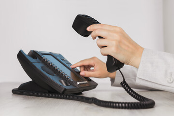 business and communications. using voip phone in the office, close up of hand with receiver. confere