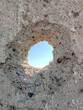 Bullet hole in a concrete wall close-up. Blue sky in the background