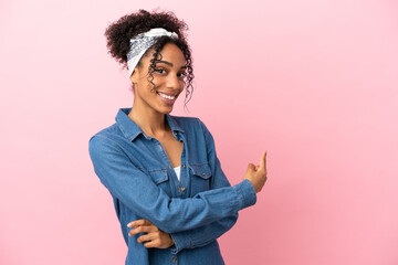 Wall Mural - Young latin woman isolated on pink background pointing back