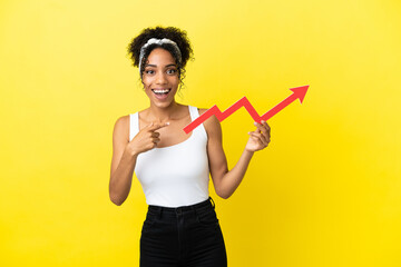 Sticker - Young african american woman isolated on yellow background holding a catching a rising arrow with surprised expression