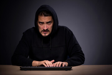 Young male hacker on grey background