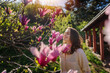 Young beautiful woman enjoying the spring of her home in the garden near a blooming magnolia tree inhaling the aroma of flowers
