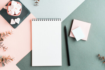 Wall Mural - Blank notepad, pencil, writing paper and marshmallows in a cup on a colored background. Top view