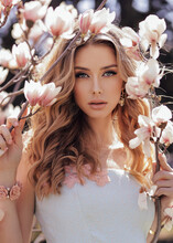 Beautiful Woman With Blond Curly Hair In Elegant Dress Posing In Spring Flowering Park With Magnolias Tree