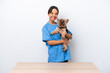 © luismolinero - Young veterinarian woman with dog on a table isolated on white background smiling a lot