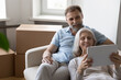 Leinwandbild Motiv Older couple relax on sofa on move day near boxes with stuff, use tablet buy goods on internet, make order via e-service app, make purchase online, search home renovation new ideas, e-commerce concept