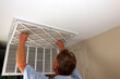 © Serenethos - Adult Male Removing Air Filter from a Home Furnace Ceiling Vent