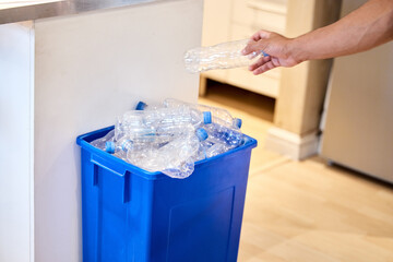 Poster - Let's look after our earth. Cropped shot of a man putting a bottle in the recycling bin at home.