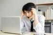 © SHUTTER DIN - young asian businessman wearing a headset feeling stressed while looking at the sceen laptop computer,