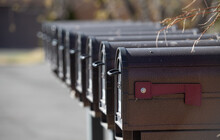 Black Metal Mailboxes In Row Line Up Of Multiple U.S. Postal Service Mail Boxes In A Row With Red Flag Of First Mail Box Down Signifying No Mail Horizontal Format Fall Background Empty Space For Type 