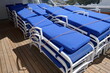 Lounge chairs with blue cushions stacked up on cruise ship wooden deck