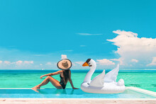 Luxury Swimming Pool Vacation Travel Lady Sun Tanning Relaxing On Infinity Ocean Waterfront Resort With Floating White Swan Inflatable Toy Float Banner Panoramic Summer Background